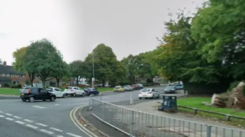A junction between two roads, pictured in the daytime from Google Street View.