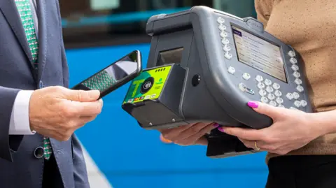 Translink A man taps his phone to a contactless machine 