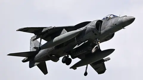 A military aircraft is seen flying in the air 