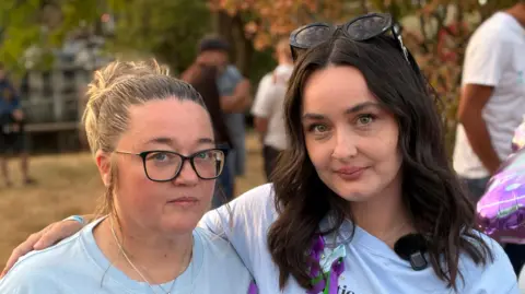 A head and shoulders image of Samantha and Charleigh Mitchell. Charleigh has her right arm around Samantha's right shoulder. They are both looking at the camera.