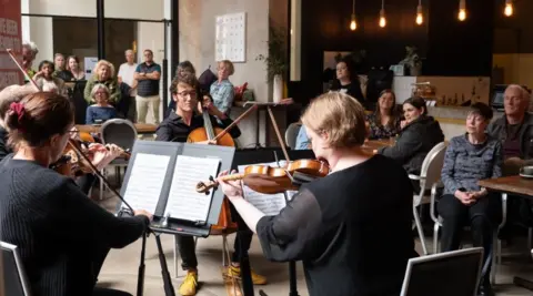 Elephant Communications A string quartet performs in a cafe while customers watch