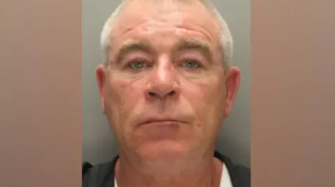 Merseyside Police A police mugshot of Vincent Coggins, in his 60s, who has blue eyes and grey hair and stares at the camera with a blank expression.