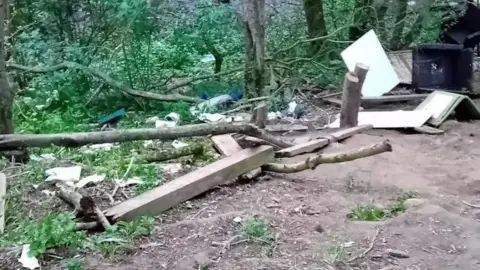 The Next Chapter Damaged fence posts, branches and rubbbish left in the woodland.