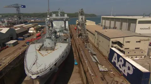 BBC There is a boat docked at the station. To the right of it, there is the collapsed crane.