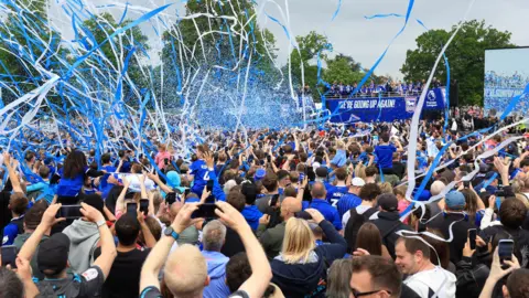 PA Media Blue and white streamers and confetti fill the air as fans celebrate the arriving open-top bus of Ipswich Town players and staff
