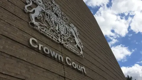 Orla Moore/BBC Exterior wall of Cambridge Crown Court showing silver coat of arms on the wall