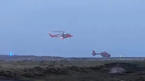Dennis Reeves Two helicopters around a coastline