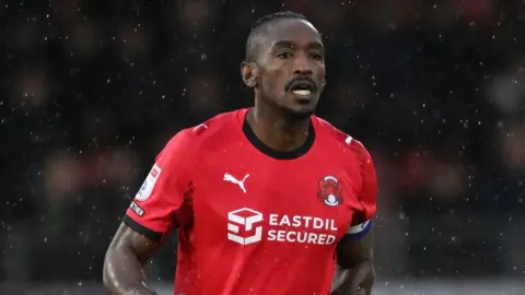 Omar Beckles running in rain in Leyton Orient home kit