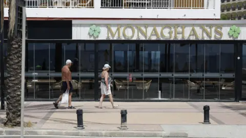 A man and woman walk past Monaghans bar in Costa del Sol