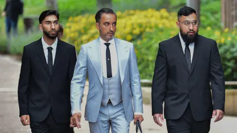 PA Media Human Rights lawyer Aamer Anwar (centre) arrives with Mohammed Fahir Amaaz (left) and Muhammed Amaad (right) at Liverpool Crown Court, where they are charged in relation to an altercation with police officers at Manchester Airport's Terminal Two on July 23 2024.
