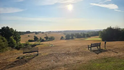 Andy B Two benches on a field overlooking rolling fields.