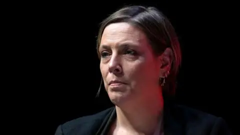 Getty Images Jess Phillips has short brown hair and is sitting at an angle against a black background. Her head and shoulders are visible, and she is wearing a black suit jacket