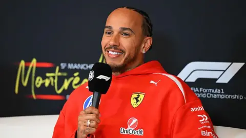 Lewis Hamilton holds a microphone in the news conference in Montreal 