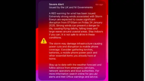 A notification screen on a mobile smart phone warning of a red weather warning for high winds in Northern Ireland on Friday. It reads: " A RED warning for wind has been issued. Extremely strong winds associated with Storm éowyn are expected to cause significant distruption from 07:00am on Friday 24 January 2025. Strong winds can present a danger to life, causing flying debris, falling trees and large waves around coastal areas. Stay infoors if you can. It is not safe to drive in these conditions.