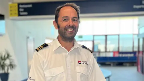 Robin Fitzgerald is wearing a Ports of Jersey uniform and is standing in the refurbished ferry departure terminal.