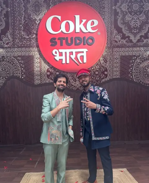 First.wav Khwab and Utpal Udit pose in front of a Coke Studio Bharat logo