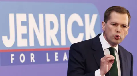 Getty Images Robert Jenrick speaking at conference in front of a sign which states Jenrick for leader