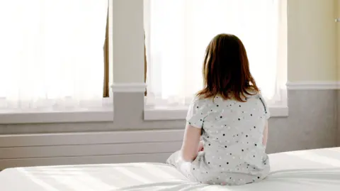 An anonymous girl sitting on a hospital bed