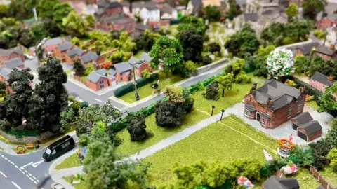 A close up of the model village which includes a tiny ostrich running up the road.