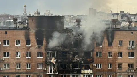 Smoke seen emerging from a burned out tower block in Kharkiv following a strike