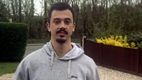 Brandon Fritz-Kessler standing on a driveway in a grey hoodie