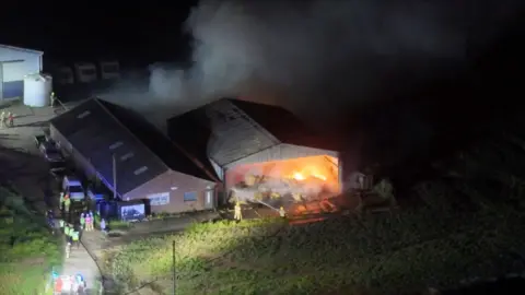 Smoke and flames rise from barn fire.