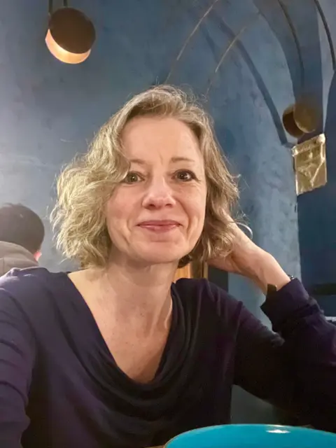 Supplied Louise wears a blue top and has short blonde hair