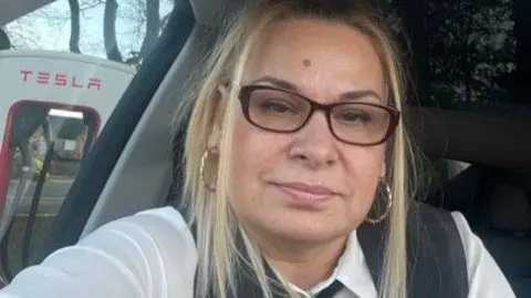 Supply a selfie of a golden haired woman sitting on the driver's seat of a car driver