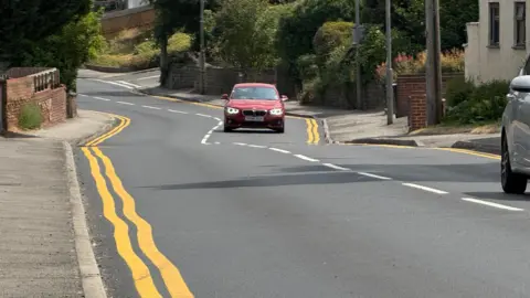 Car driving along road with wobbly yellow lines.