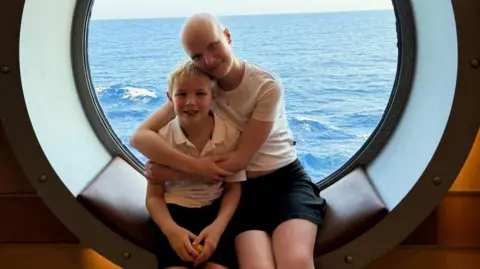 PA Media/Family Handout Mateo and Liz sit on a padded seat in the window of a ship. Liz has her arms around Mateo and they are both smiling at the camera.