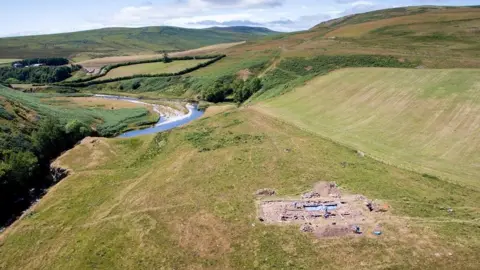 Ian Glendinning  An overhead image of an archaeological dig with a river and hills behind