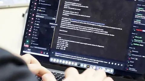 A computer keyboard with code on it and the operator's hands.
