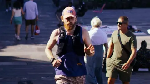 Richard Stennett running in an urban area with people walking in the background