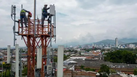 Getty Images Workers inspecting 5G antennas