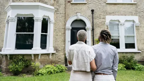 Getty Images Rear view of a couple looking at a restored Victorian house