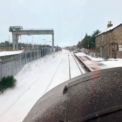 Network Rail Snow on a railway track at a station. The photo has been taken from the front of a train