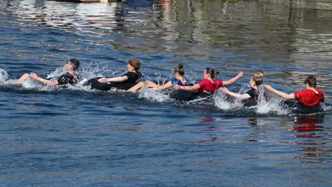 MANX SCENES Water splashing up around a team of competitors in the snake race as they paddle using their arms.