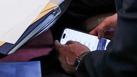 Reuters Mike Waltz's hands holding an iPhone showing Signal chats