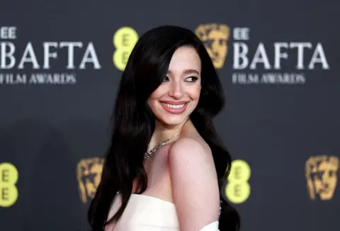 Reuters Mikey Madison was all smiles on the red carpet. She is wearing a cream sleeveless dress.