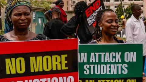 Getty Images Two women protesters hold banners to protest recent school abductions in Nigeria