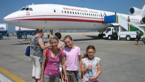 Tandem Travel Helen stands with her two daughters in front of the plane equivalent to Polish Air Force One