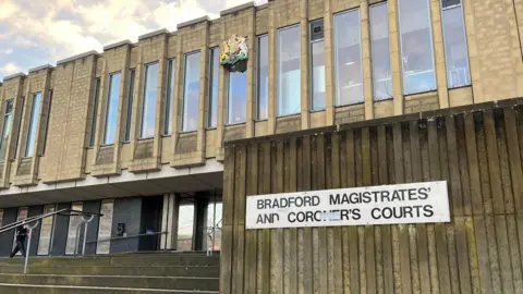 A picture of Bradford Magistrates' Court. The building has steps going up to the doorway and a sign outside which reads 'Bradford Magistrates' and Coroner's Court'