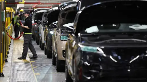 Reuters A factory worker assembling vehicles at a Jaguar Land Rover factory site