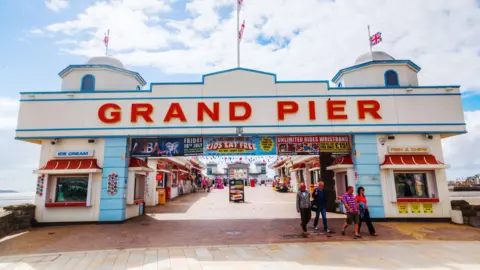 Getty Images The Grand Pier entrance with people walking out and the sea in the background