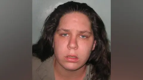 Met Police Tracey Connelly, a woman with long dark curly hair looks at a camera for a police custody shot