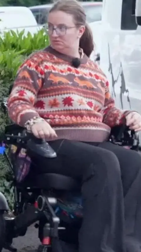 Woman in a wheelchair wearing a pattern jumper 