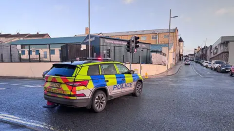 A police car parked at a junction of a road.