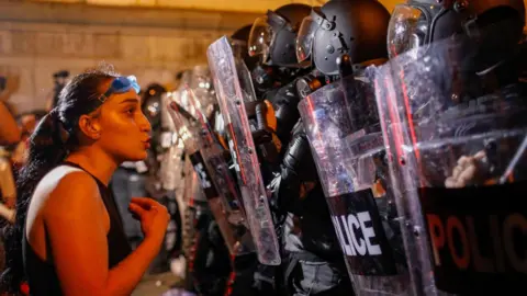 EPA-EFE/REX/Shutterstock A female protesters confronts riot police in Tbilisi, Georgia. Photo: April 2024