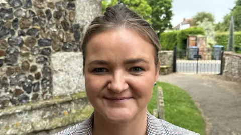 Ben Parker/BBC Jenny Riddell-Carpenter smiles at the camera. She has dark blonde hair that is tied back. 
