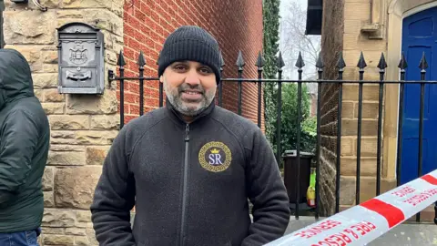 Alex Moss/BBC Habib Akhtar, who is wearing a black beanie hat and a black zip-up jumper.